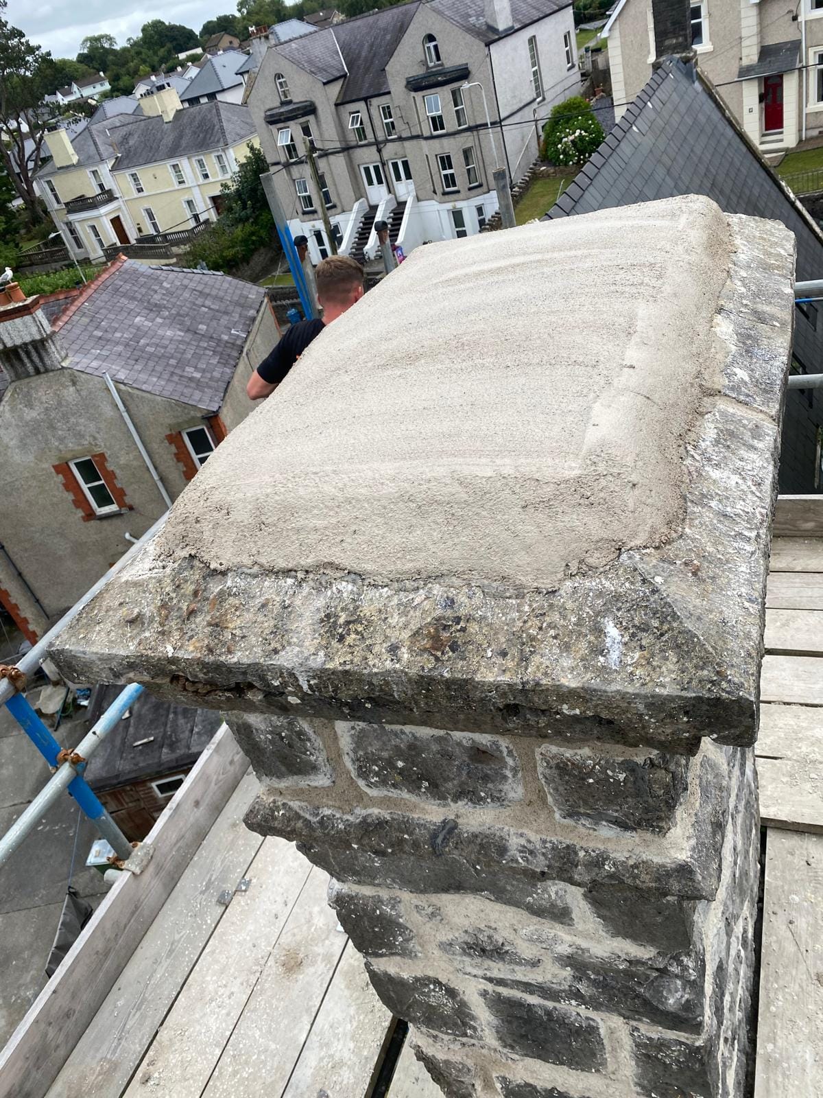 Restored stone chimney stack with new lime flaunching on a listed building