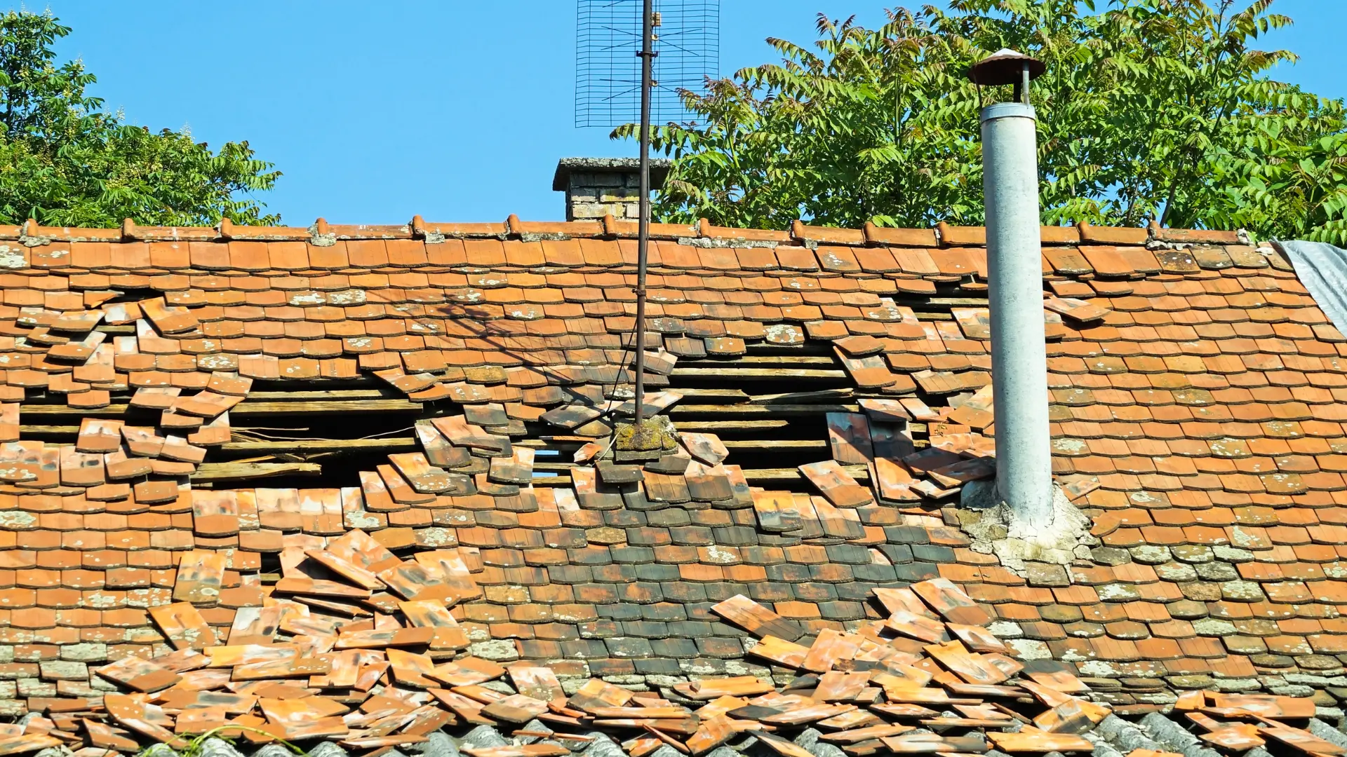 Storm-damaged tiled roof with slipped and broken tiles exposing the roof battens