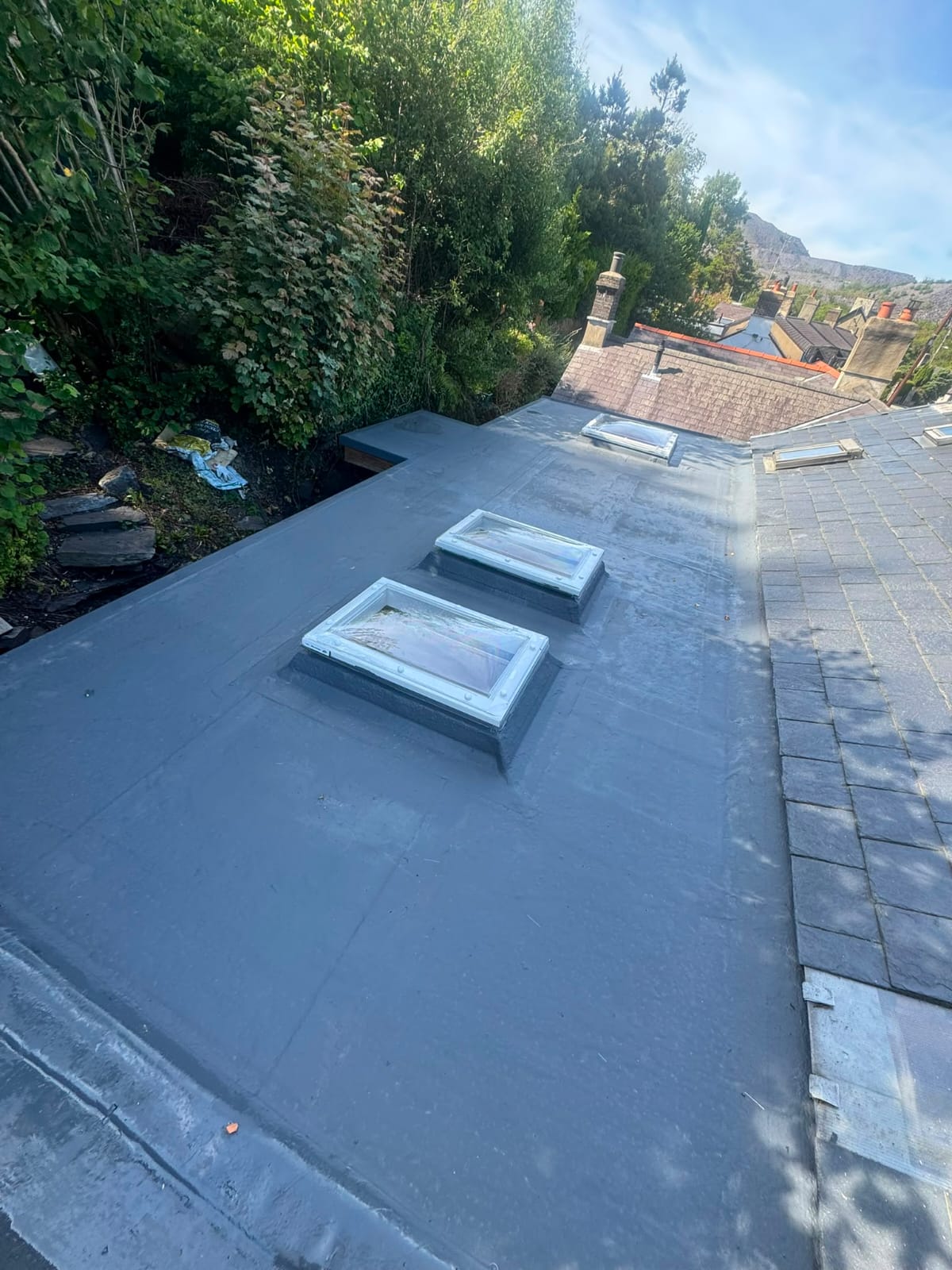 Grey liquid-applied flat roof with three new skylights fitted